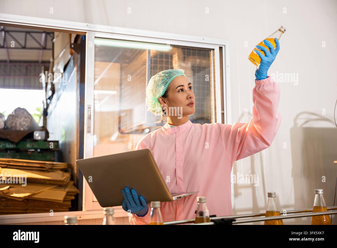 Female manufacturer inspects beverage bottles on a conveyor belt in the ...
