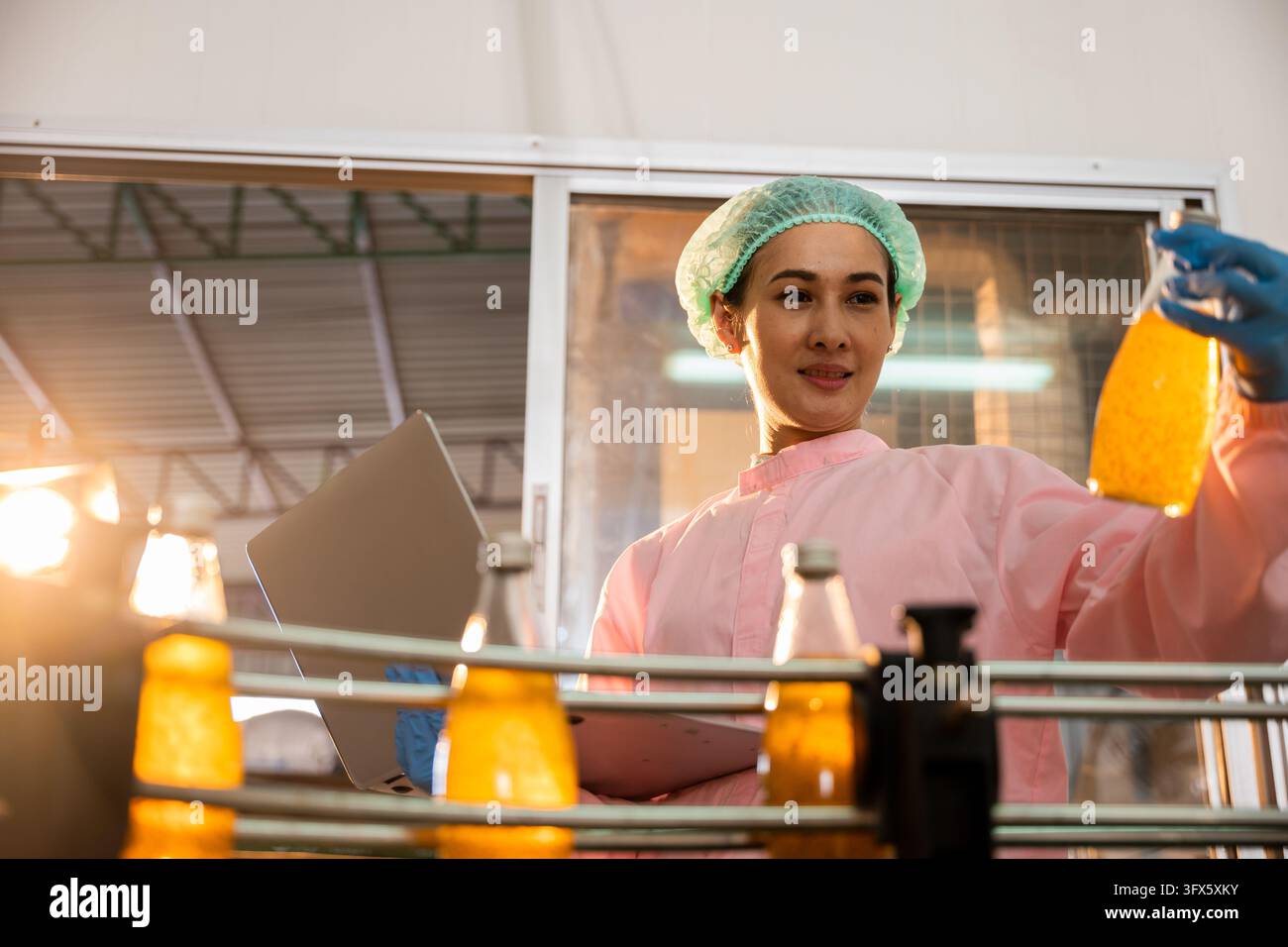 Woman scientist checks bottles on conveyor using laptop in beverage ...