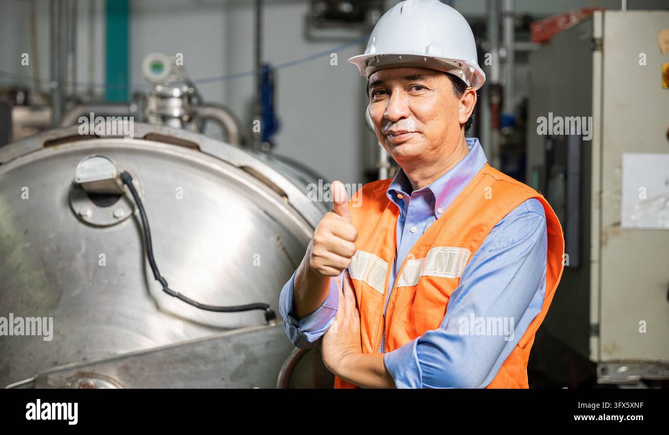 Engineer showing thumbs up sign while smiling inside water treatment ...