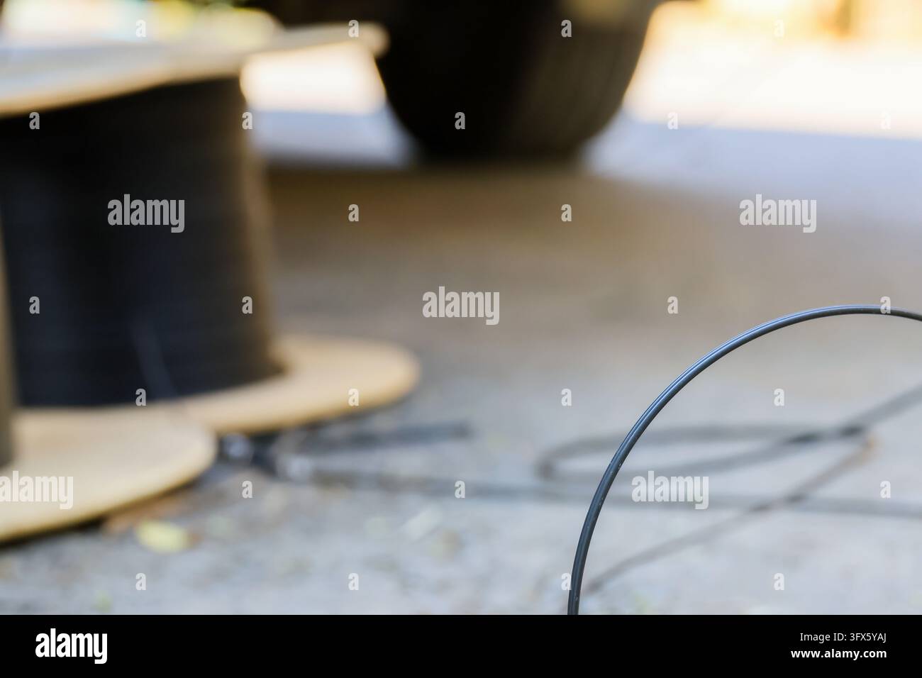 A curved fiber cable beside black spool on workshop table, with soft ...