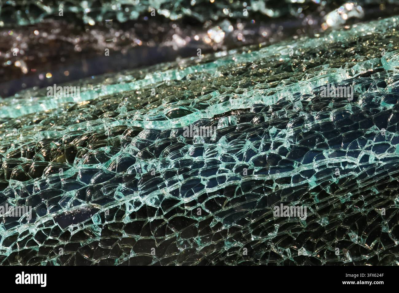 A shattered glass surface with turquoise reflection and intricate ...