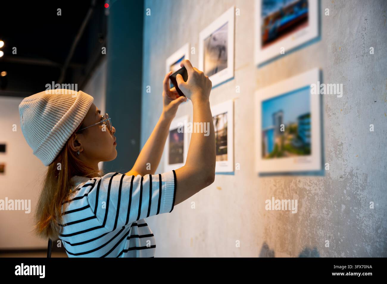 Visitor woman standing takes picture art gallery collection in front ...