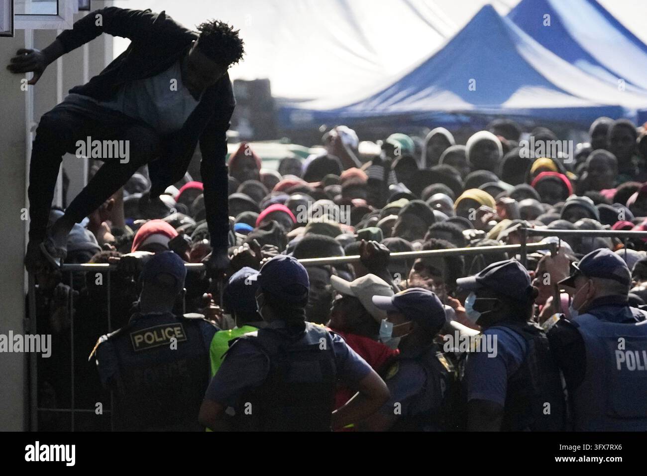 FILE - A Malawian migrant jumps over a barricade as the police officer ...