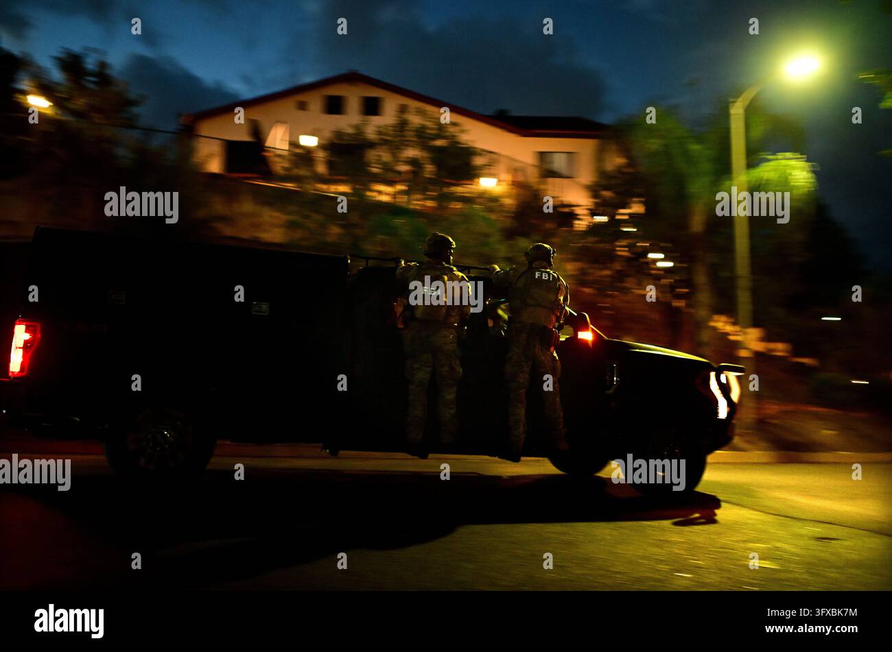 Federal agents arrive to a suspect's house during a raid related to ...