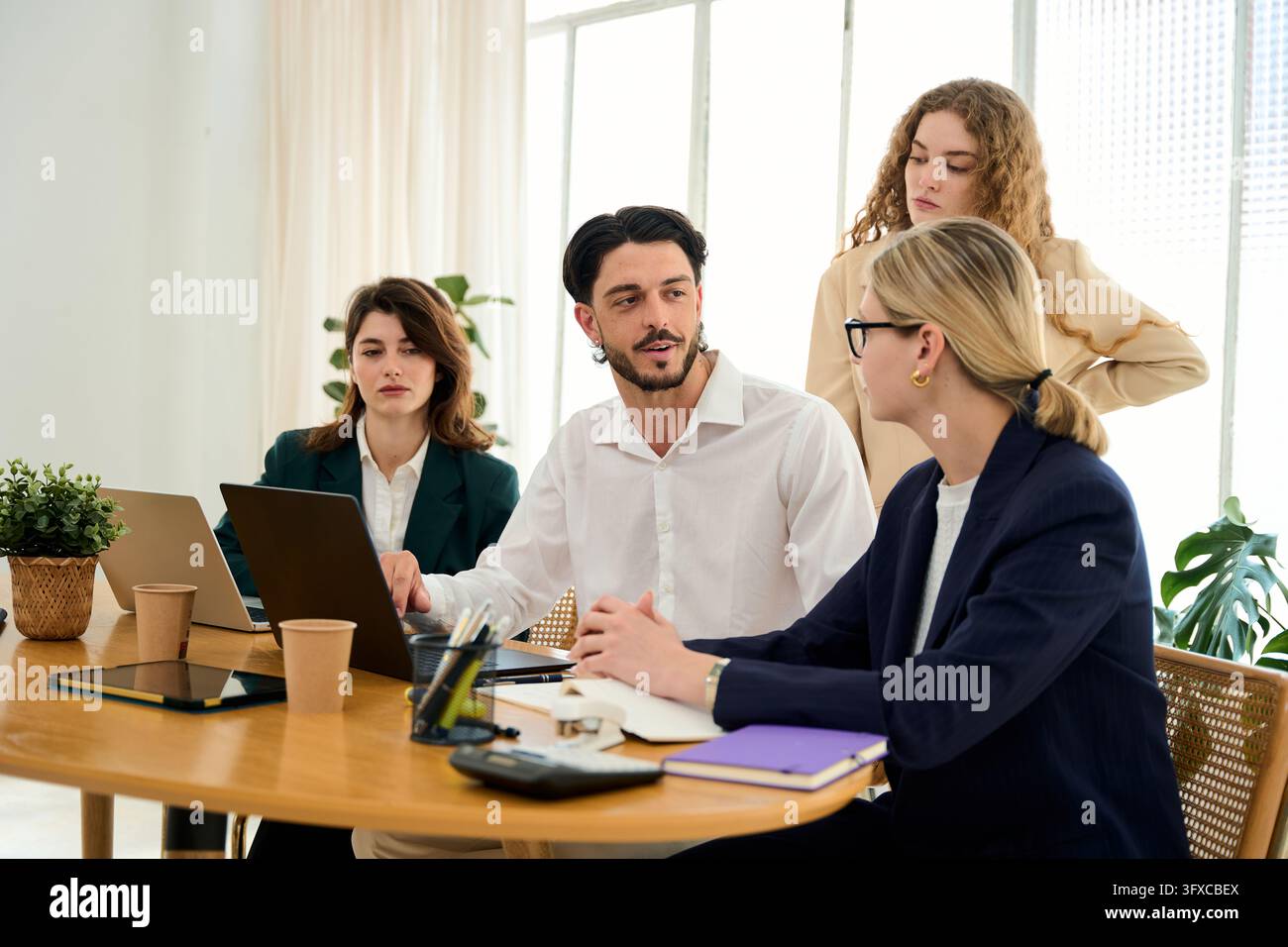 Diverse team of professionals collaborating, discussing project strategies, and working together in a modern office environment Stock Photo