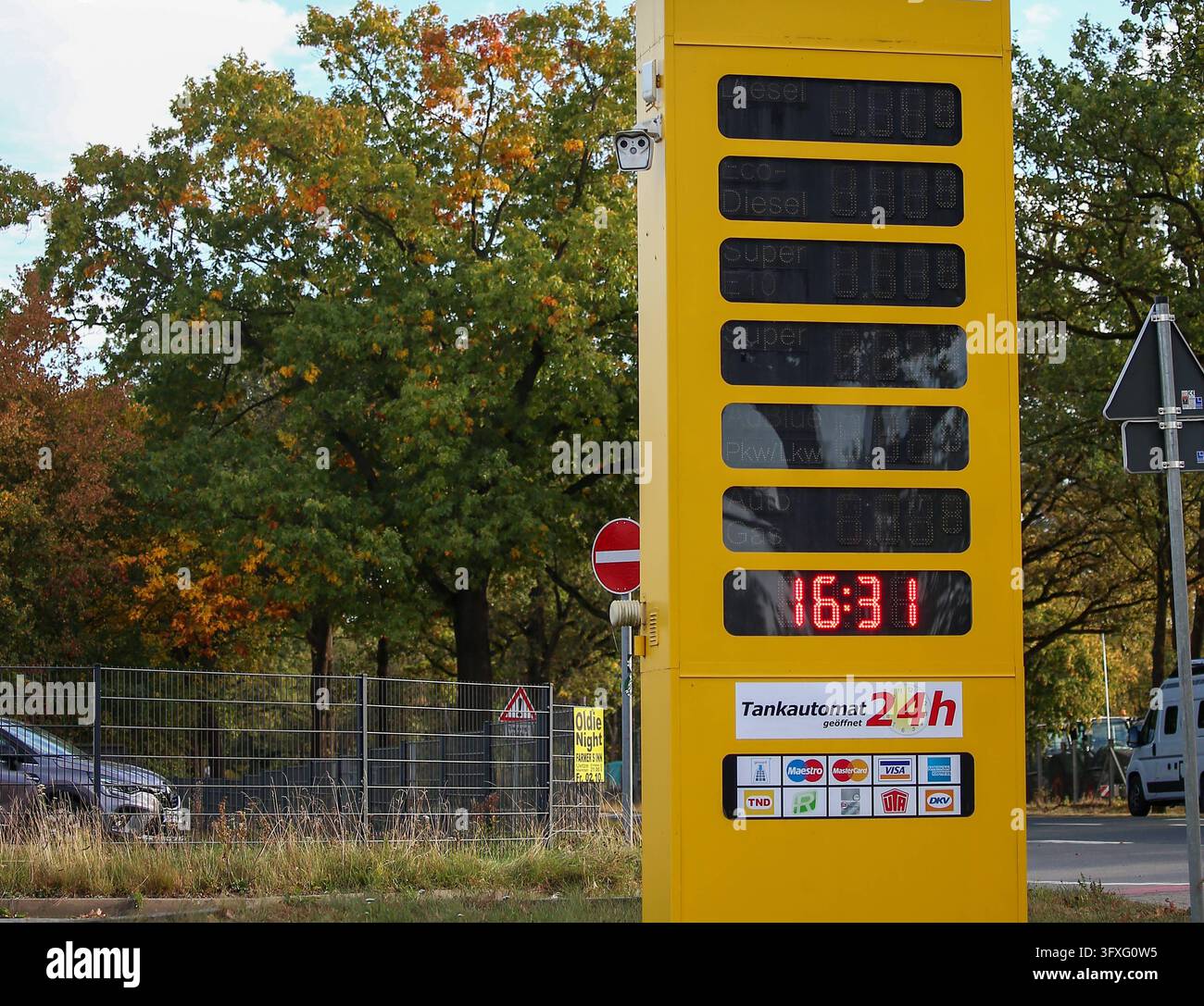 Deutschland, Europa: Eine gelbe Tankstellensäule zeigt eine Uhr sowie ...