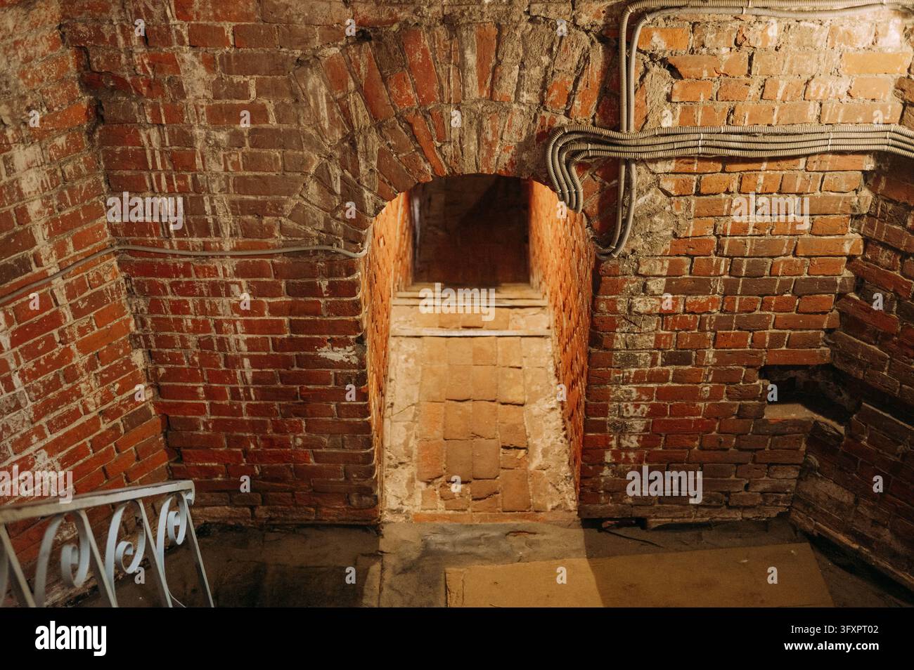 Old brick archway with narrow stone steps in a historic underground passage Stock Photo