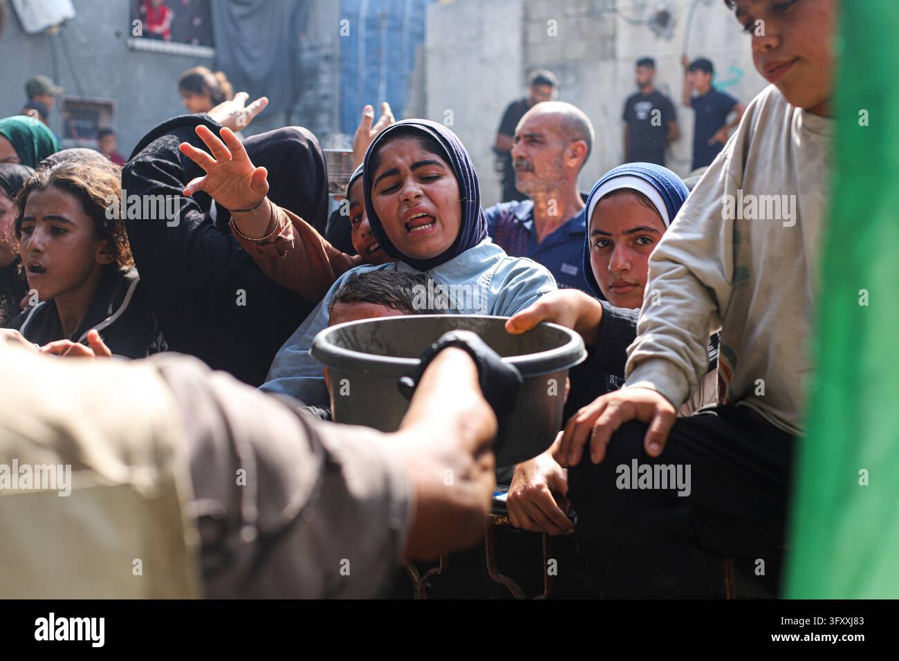 Palestinian women reach forward as food is handed out at a charity ...