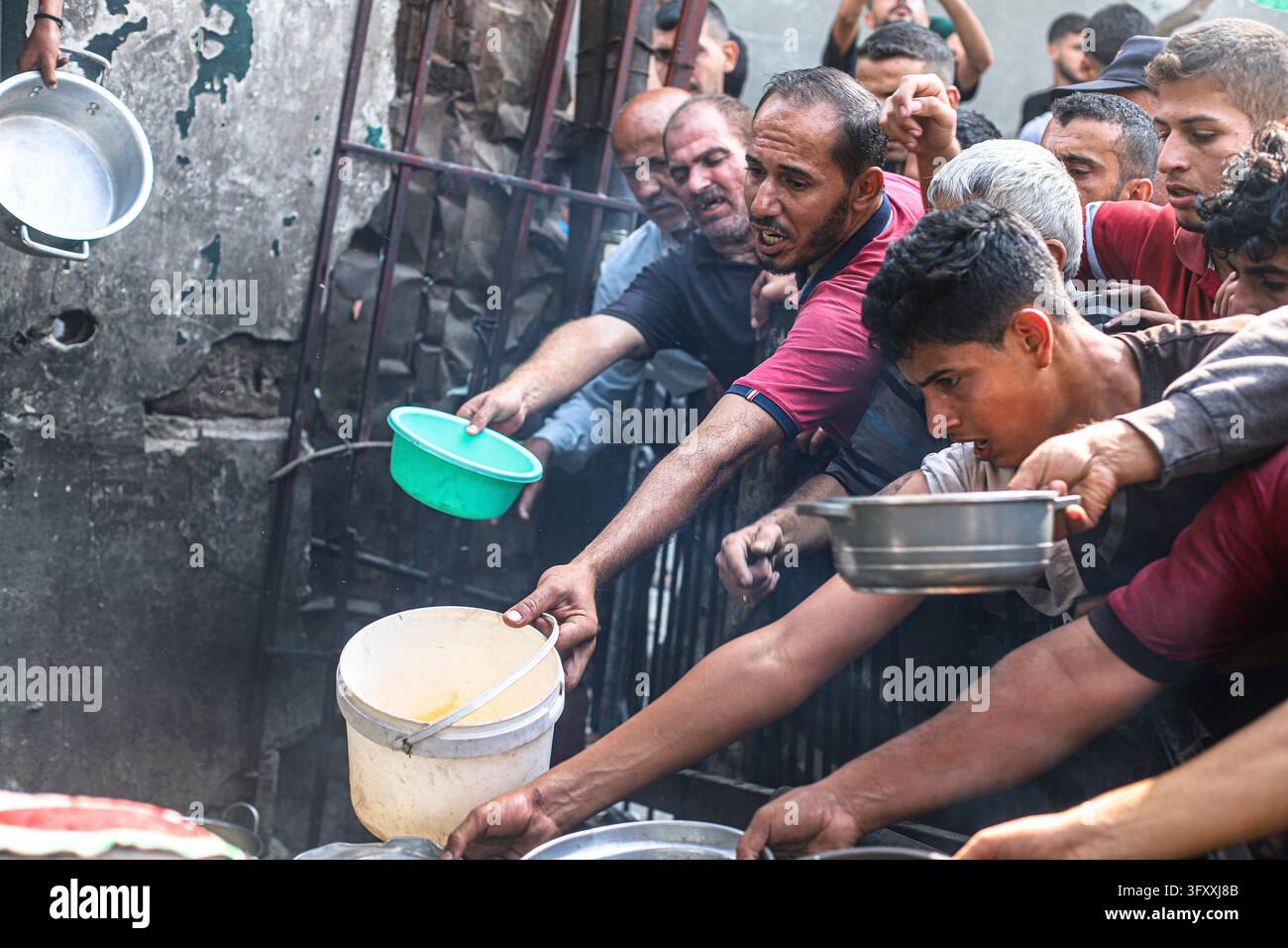 Palestinians press toward a charity kitchen carrying pots and bowls to ...
