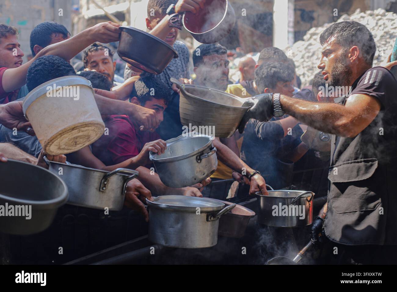 Palestinians press toward a charity kitchen carrying pots and bowls to ...