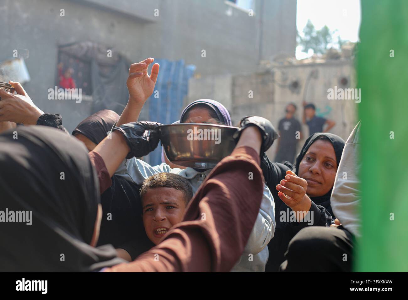 Palestinian women reach forward as food is handed out at a charity ...