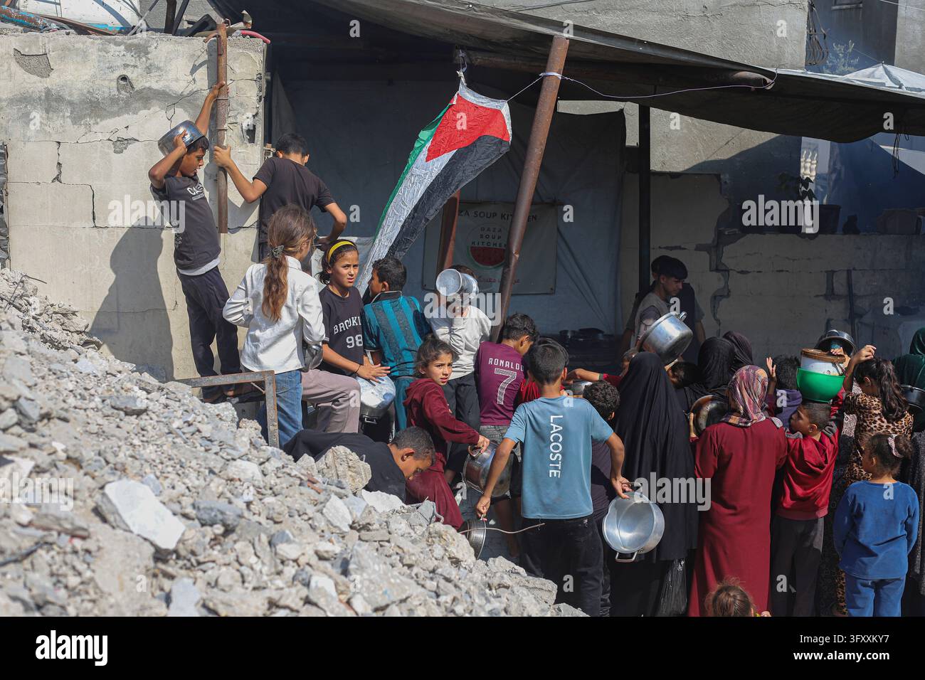 Palestinians, including children, queue with cooking pots at a charity ...
