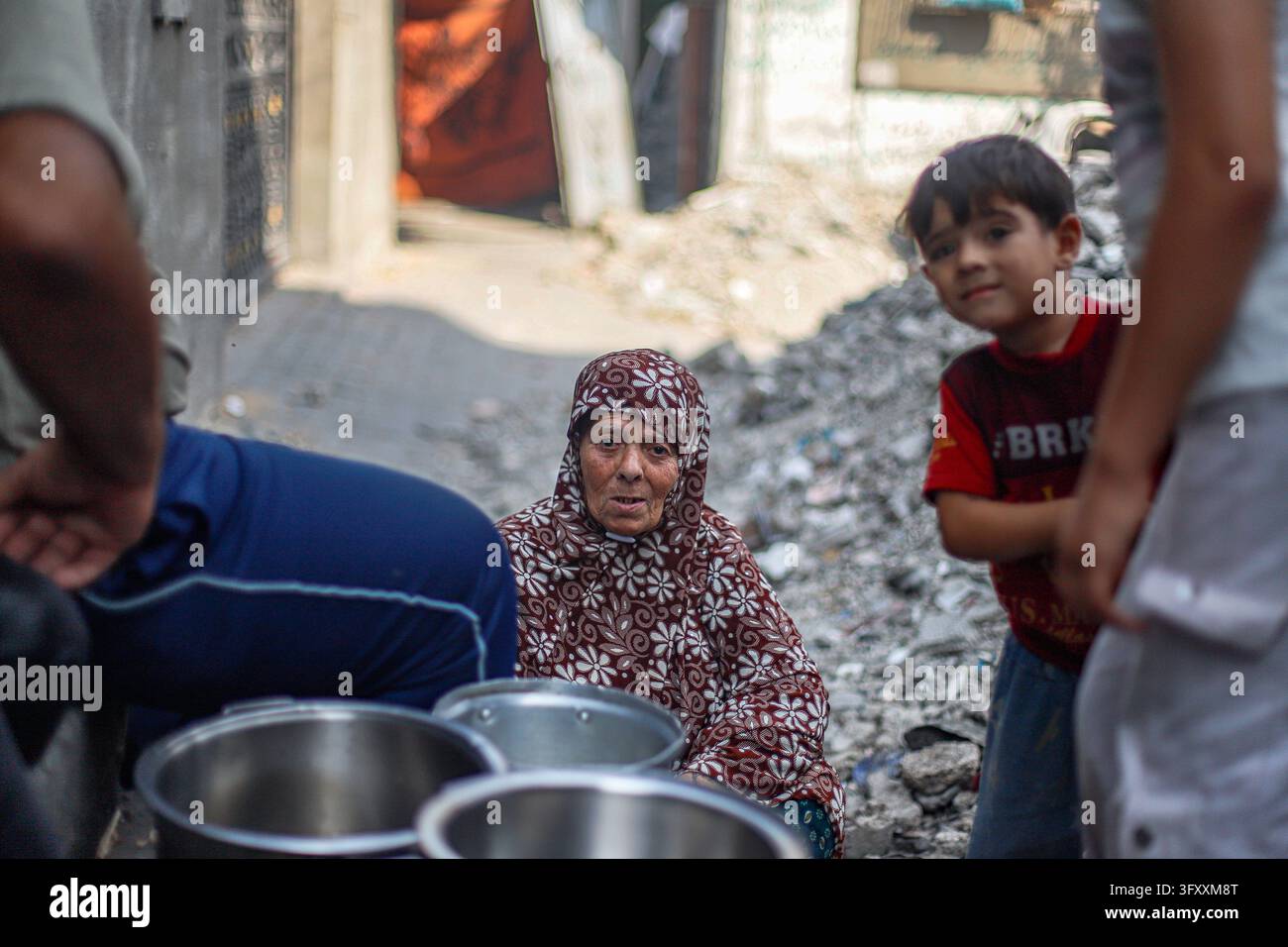 Palestinians wait with metal cooking pots at a charity kitchen in ...