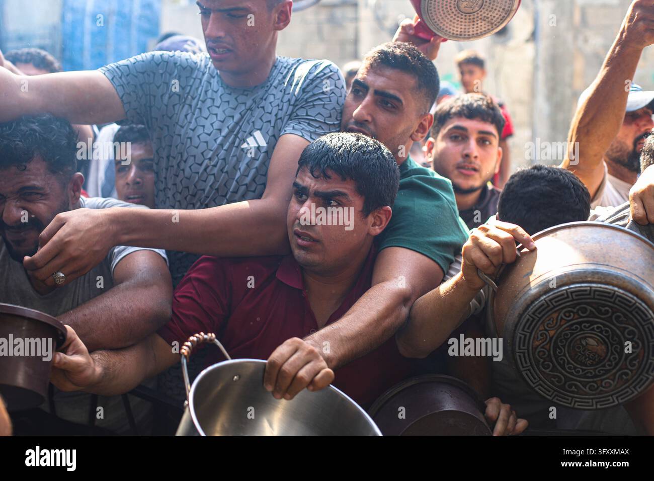 Palestinians press toward a charity kitchen carrying pots and bowls to ...