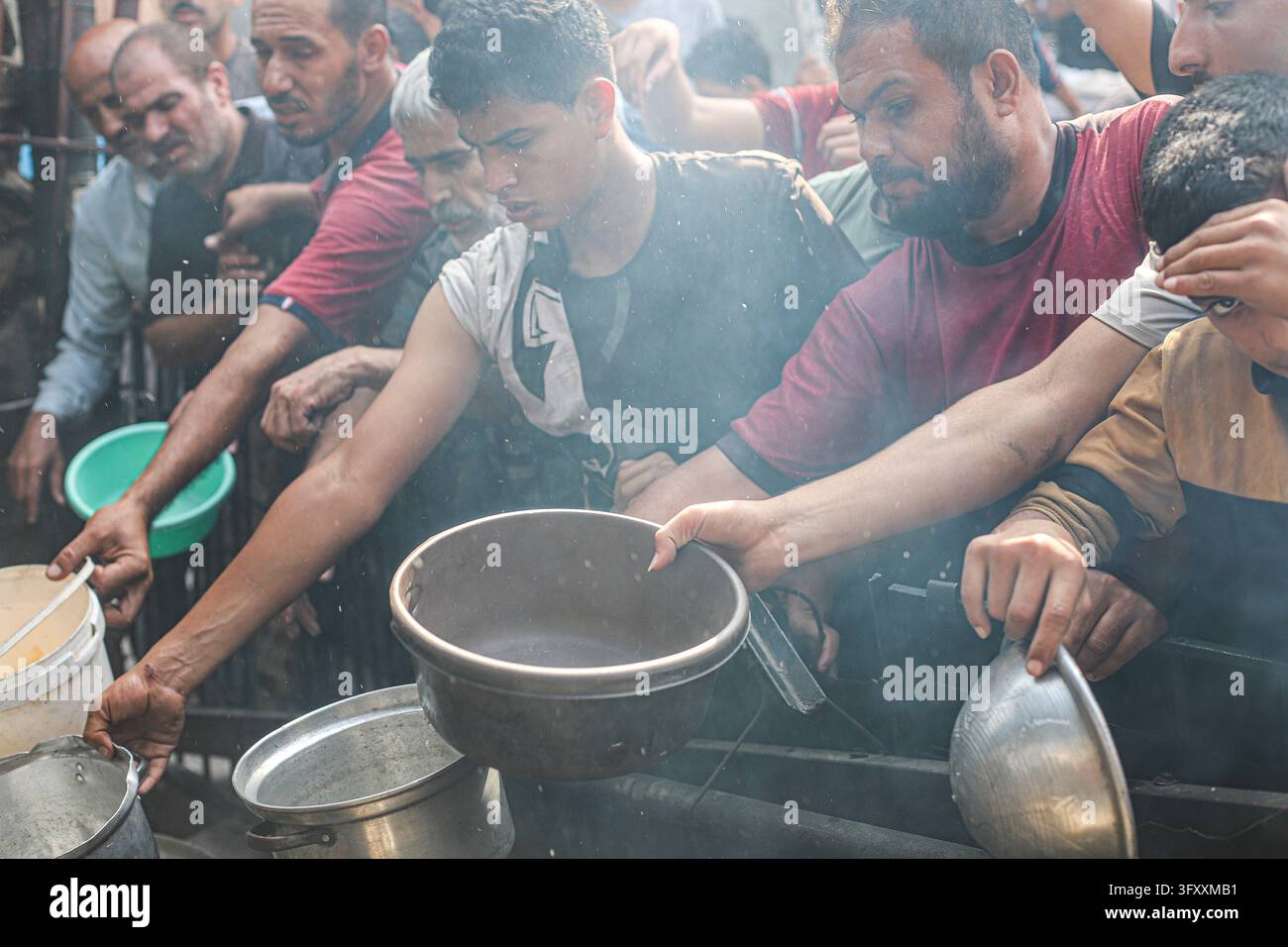 Palestinians press toward a charity kitchen carrying pots and bowls to ...