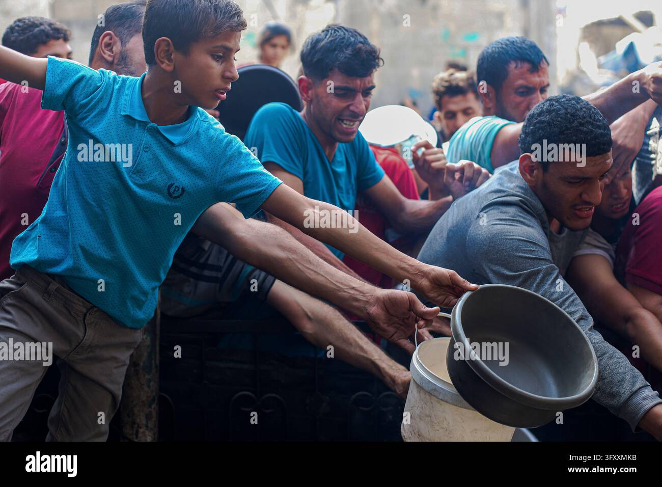 Palestinians press toward a charity kitchen carrying pots and bowls to ...