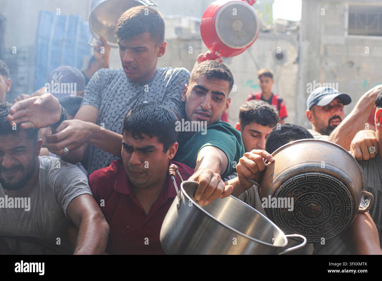 Palestinians press toward a charity kitchen carrying pots and bowls to ...
