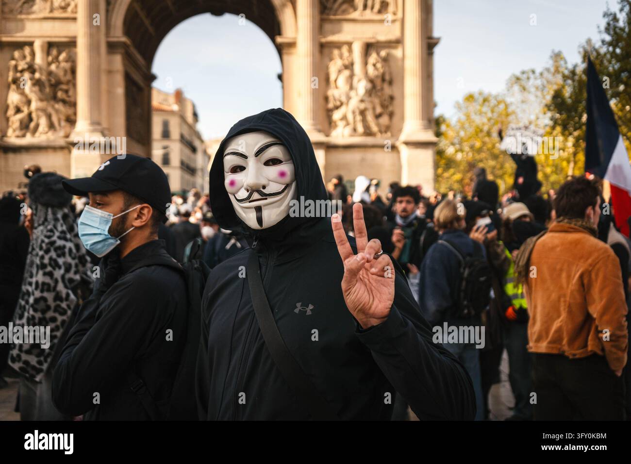 A demonstrator wearing a Guy Fawkes mask makes a hand gesture during a ...