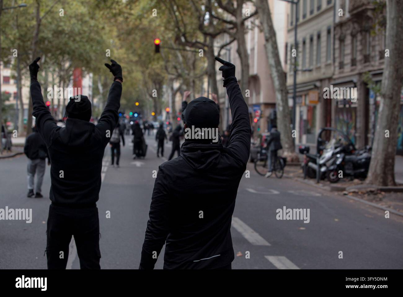 Two masked protesters raise their middle fingers toward police officers ...