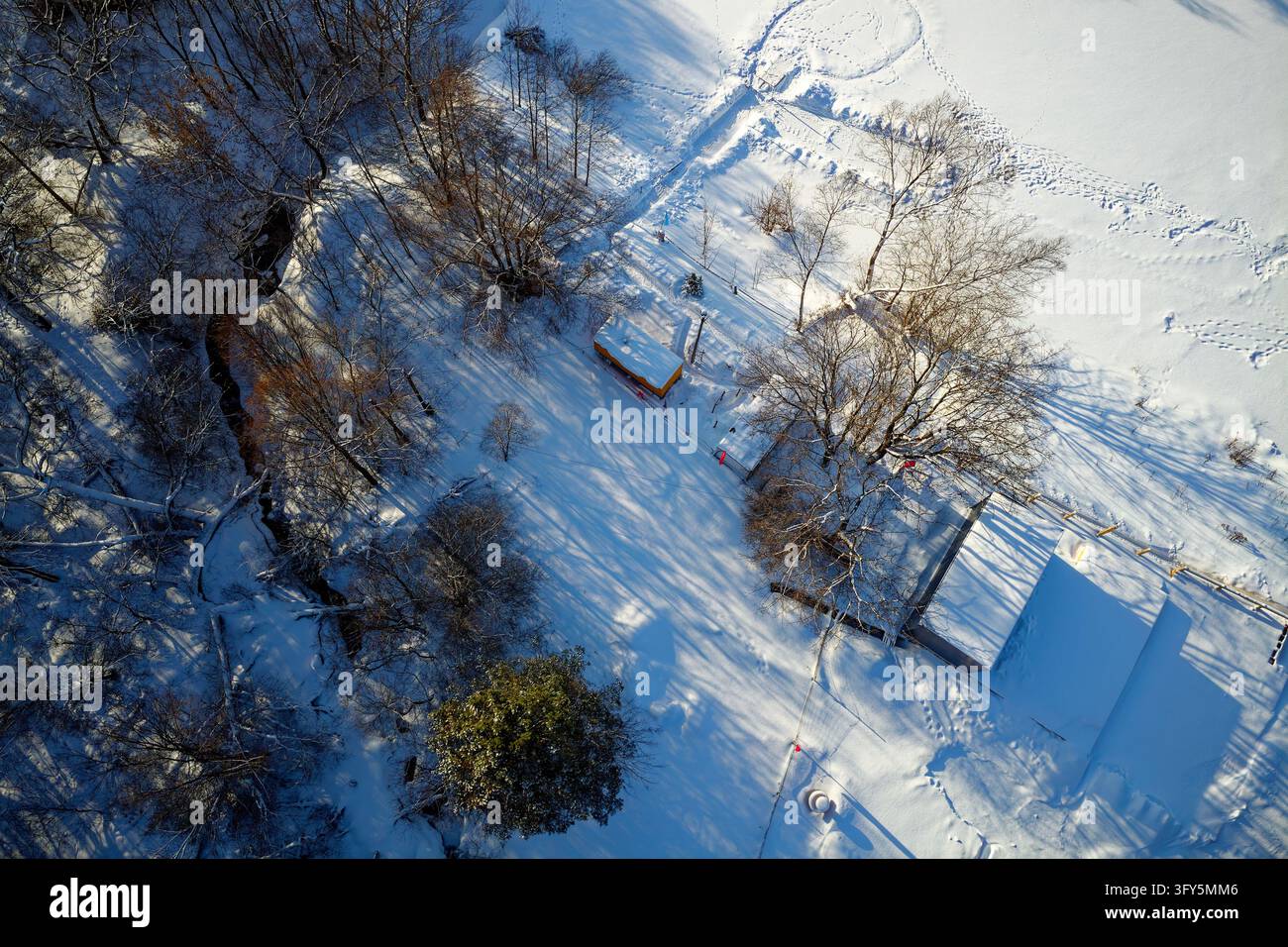 Aerial top view of small site huts nestled in a deep snowy riverbank ...