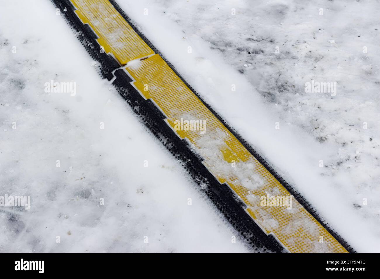 Yellow and black cable protector ramp partially covered with fresh ...