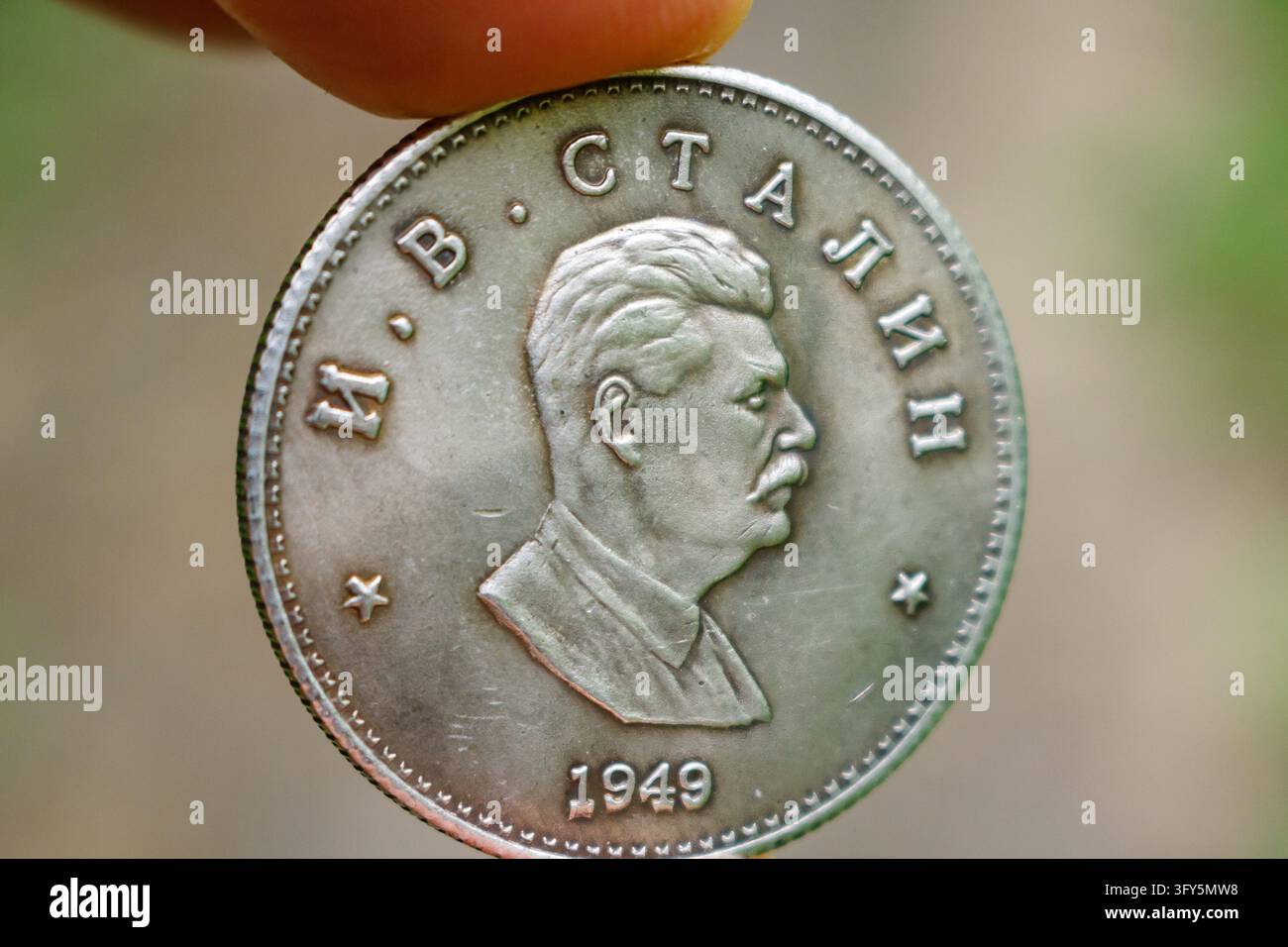 Fingers holding shiny souvenir coin with Joseph Stalin profile portrait ...