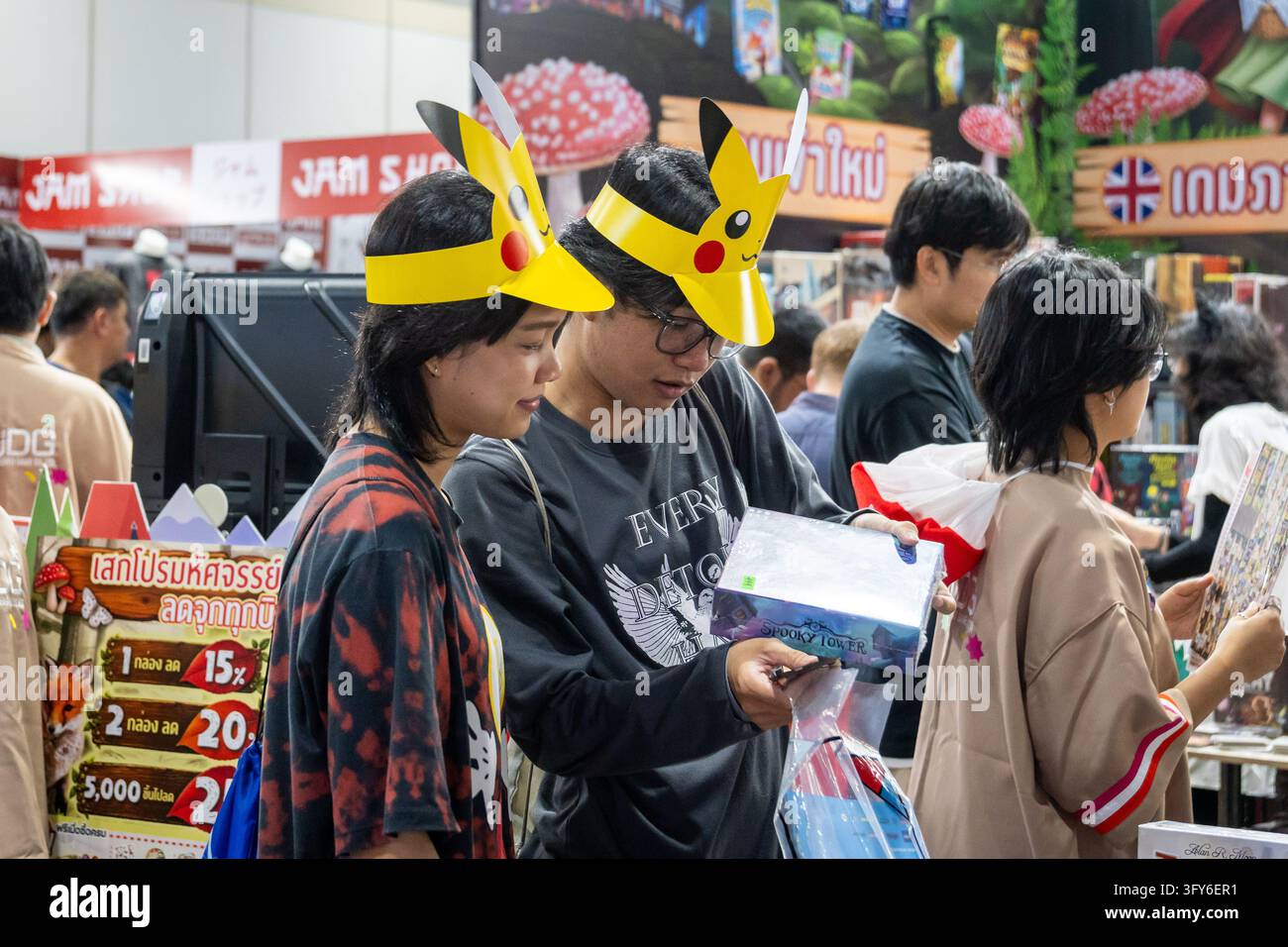 Pikachu Vector Graphics Two visitors wearing Pikachu paper visors look at a boxed board game at ...