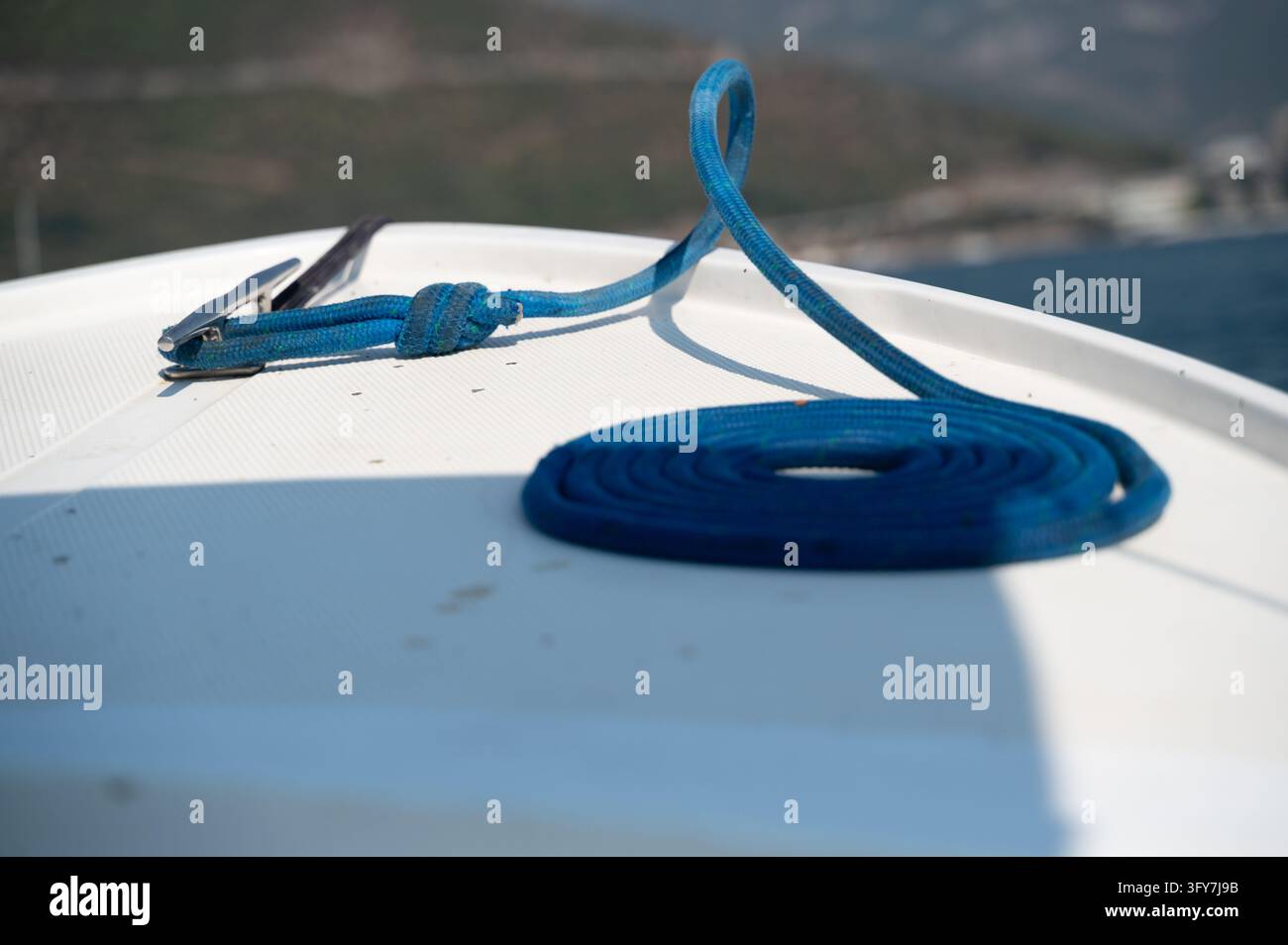 Maline Rope Close-up of blue mooring rope coiled and laid on white fiberglass boat ...