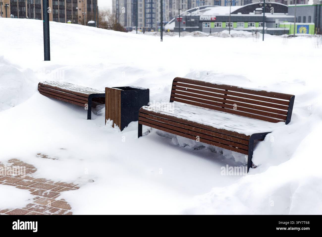 Empty wooden benches covered with fresh white snow in a quiet winter ...