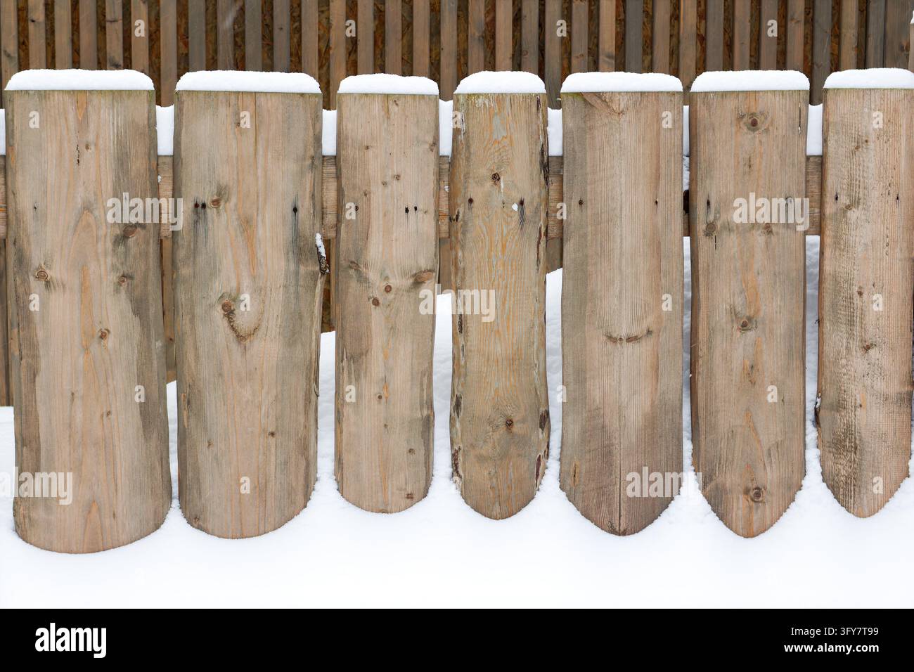 Weathered wooden fence planks covered with caps of fresh white snow ...