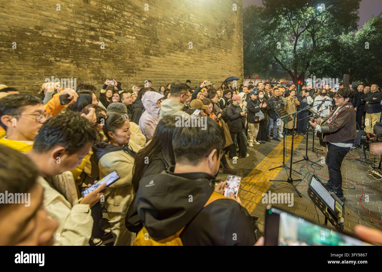 Tourists watch a rock band performing in the park of Yongning Gate, the ...
