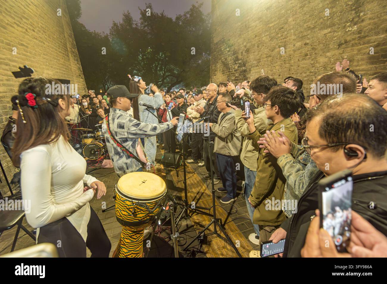 Tourists watch a rock band performing in the park of Yongning Gate, the ...