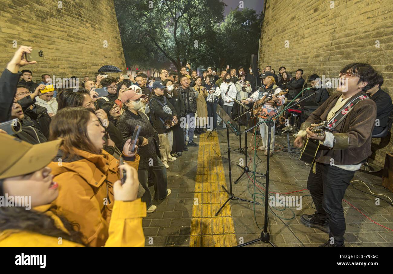 Tourists watch a rock band performing in the park of Yongning Gate, the ...
