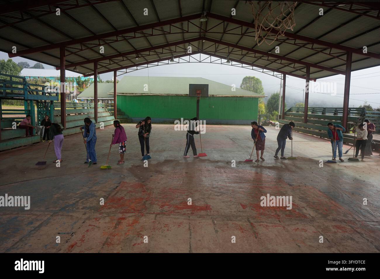 Women sweep the basketball court in preparation for the Day of the Dead ...