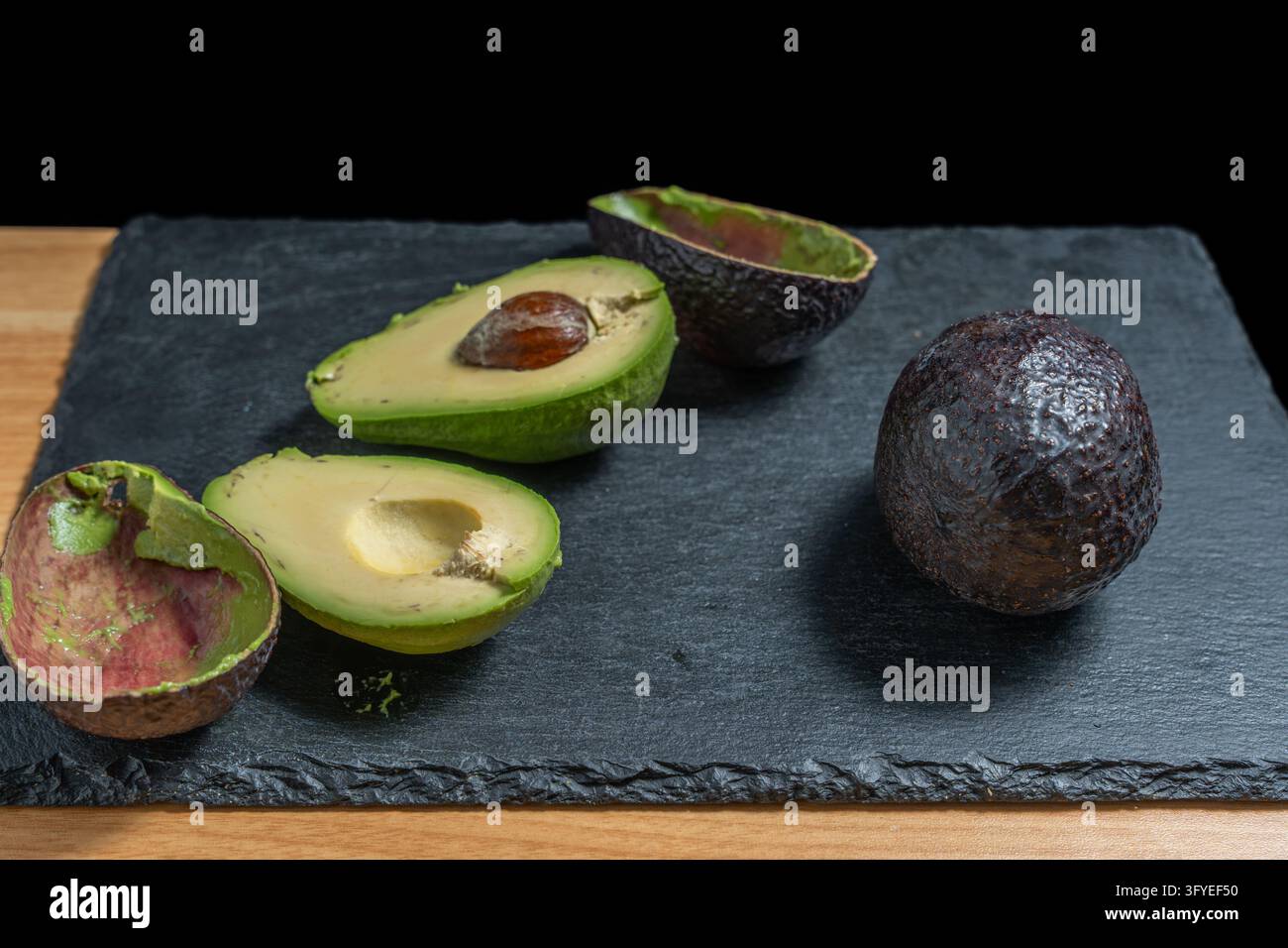 Two peeled avocado halves, one with the pit, two empty avocado skins ...