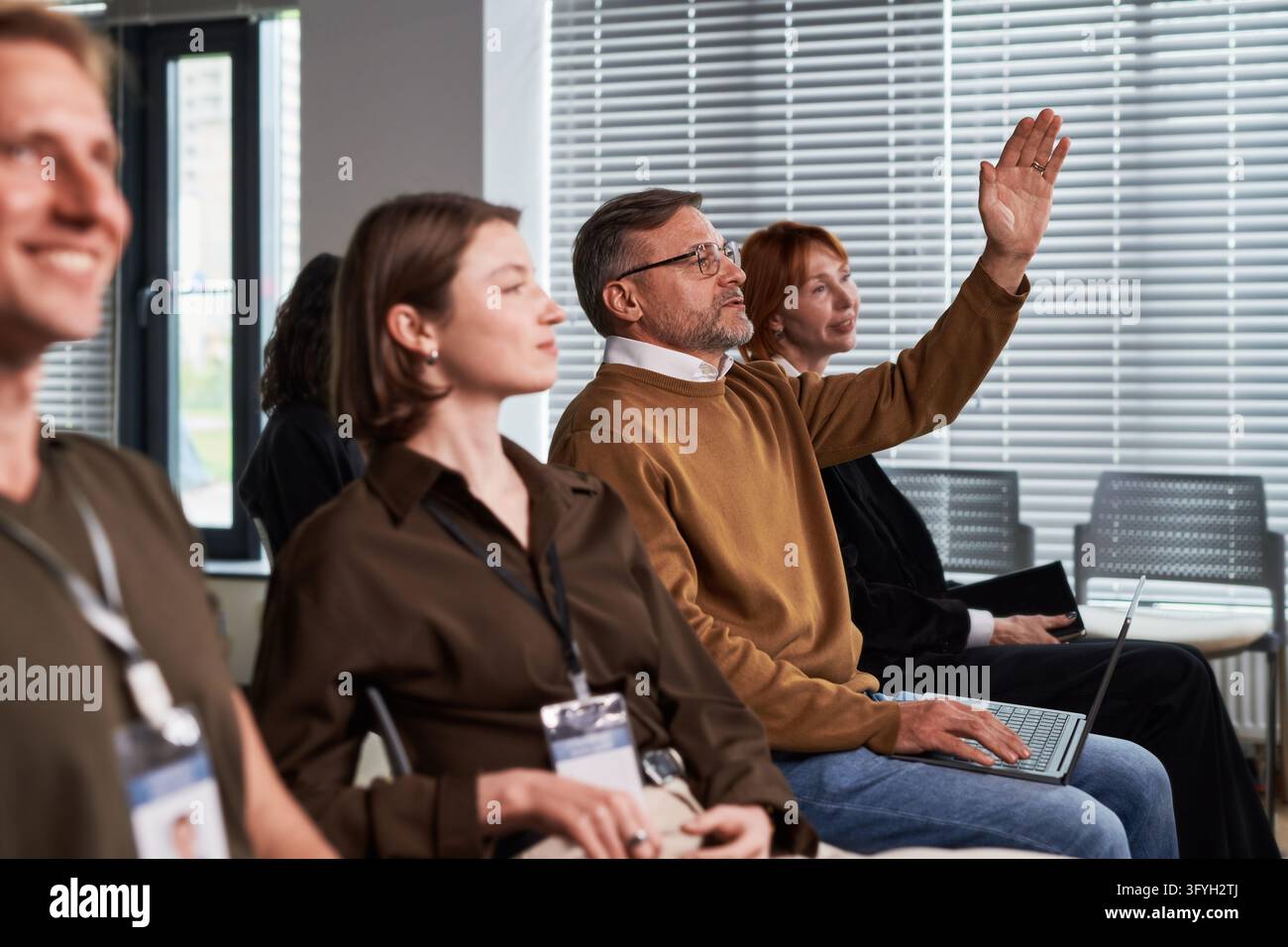 Middle Aged Businessman Raising Hand at Corporate Conference Stock Photo