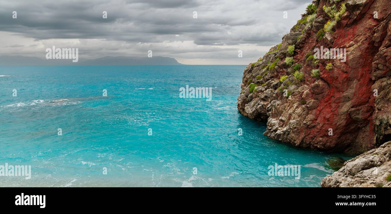 Turqoise Neon Bright turquoise water fills a quiet inlet beside a steep, weathered ...