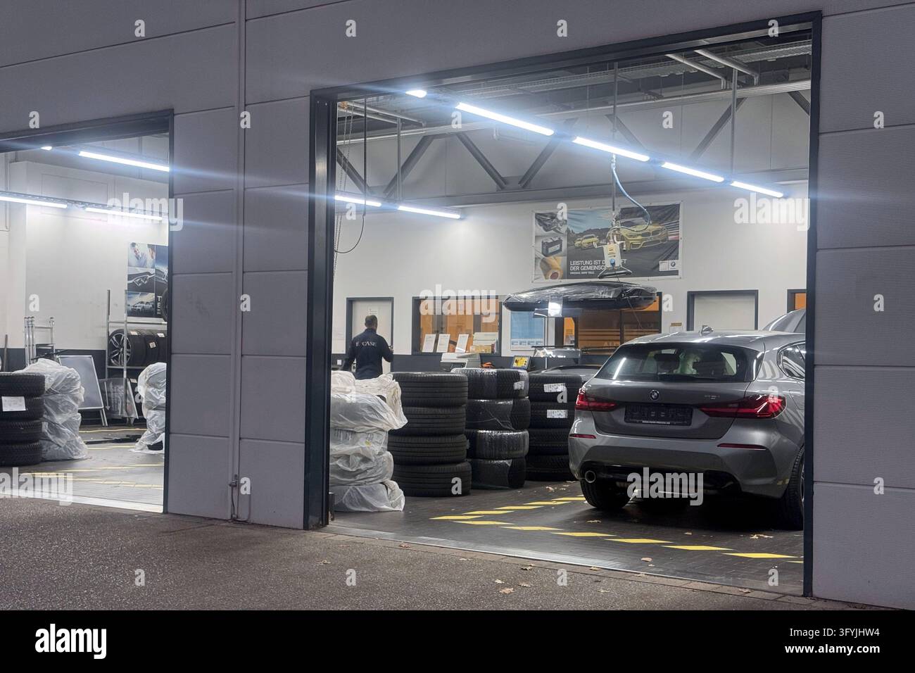 Modern car repair shop with open garage doors, tire storage, and a ...