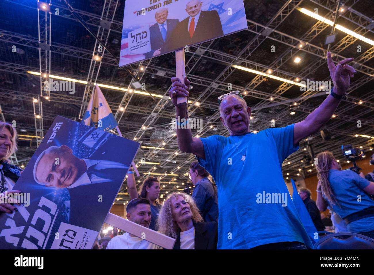 A Likud supporter raises a campaign placard featuring Donald Trump and ...