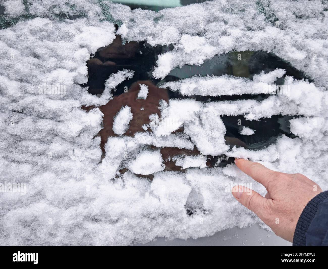 Snow covers a parked car during winter, with frost and ice on the ...