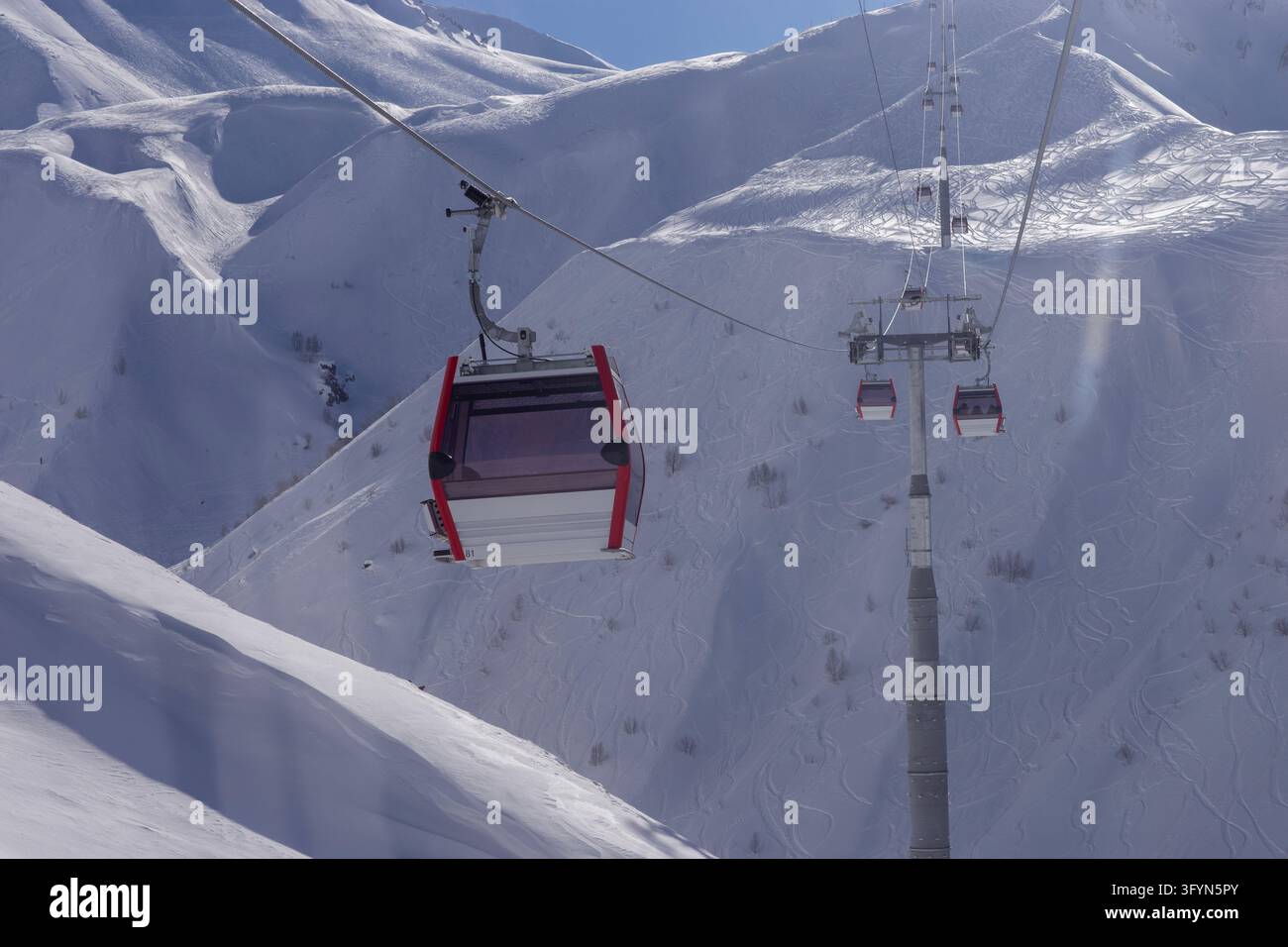 Red and white cable car cabin moving on a ropeway over magnificent snow ...