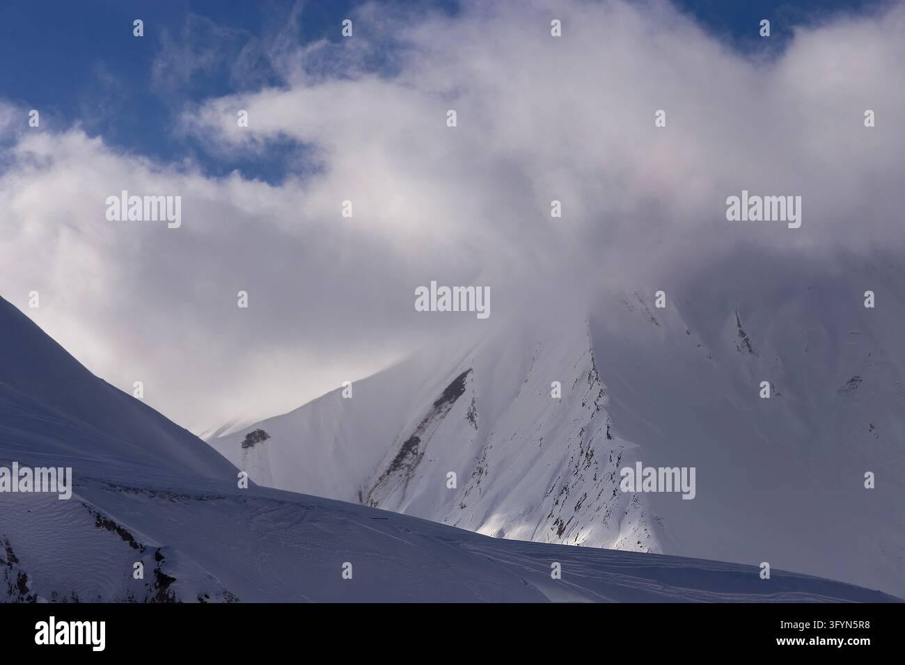 Majestic snow-covered mountain peaks enveloped in thick white dramatic ...