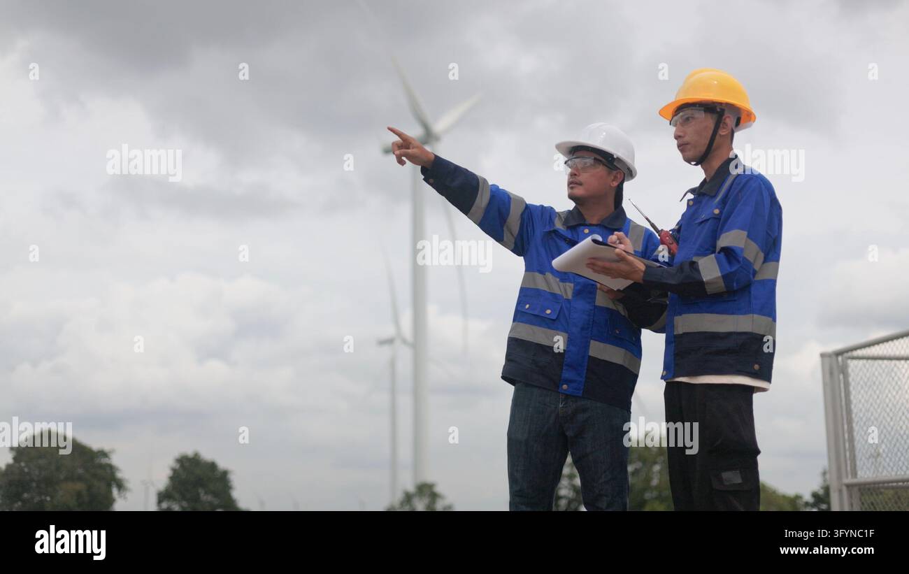 Two Asian male engineers in safety uniform and hard hat inspecting wind ...