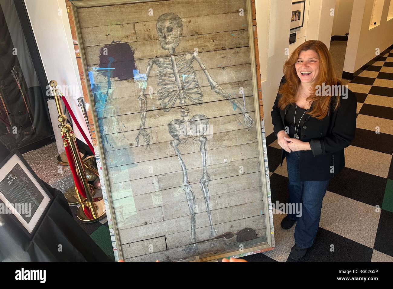 AddamsFest founder Dawn Mackey stands beside a skeleton drawing Charles ...