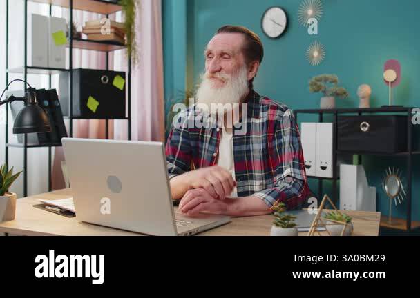 Thoughtful concerned Caucasian senior man working on laptop computer ...