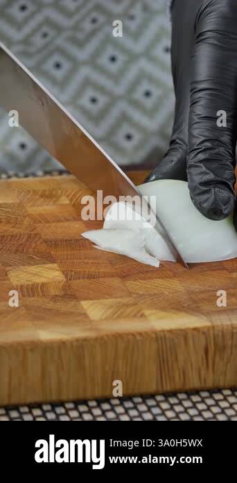 Vertical video screen. Food preparation. Cook with a chefs knife slices ...