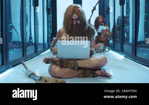 A caveman is sitting comfortably on the floor, intently using a sleek ...