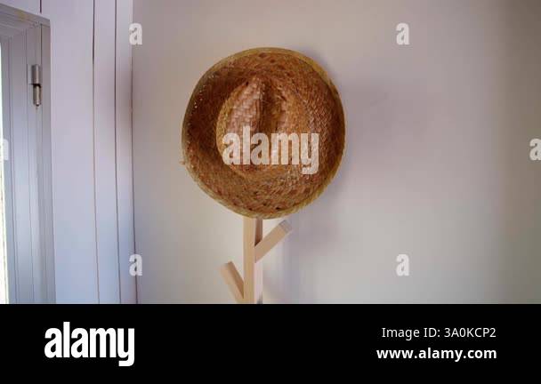 Two straw hats, one natural brown and one white, hanging on minimalist ...