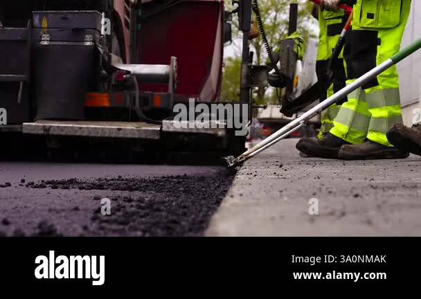 Worker Levels Asphalt Freshly Spread on Gravel with an Asphalt Screed ...
