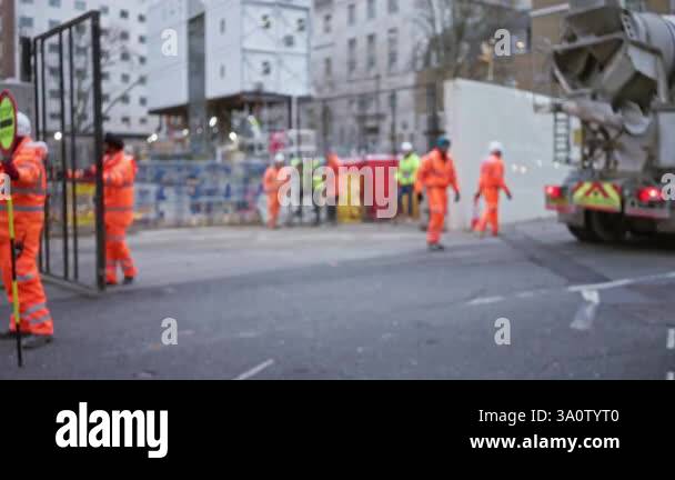 Workers in orange uniforms and helmets at a construction site with ...